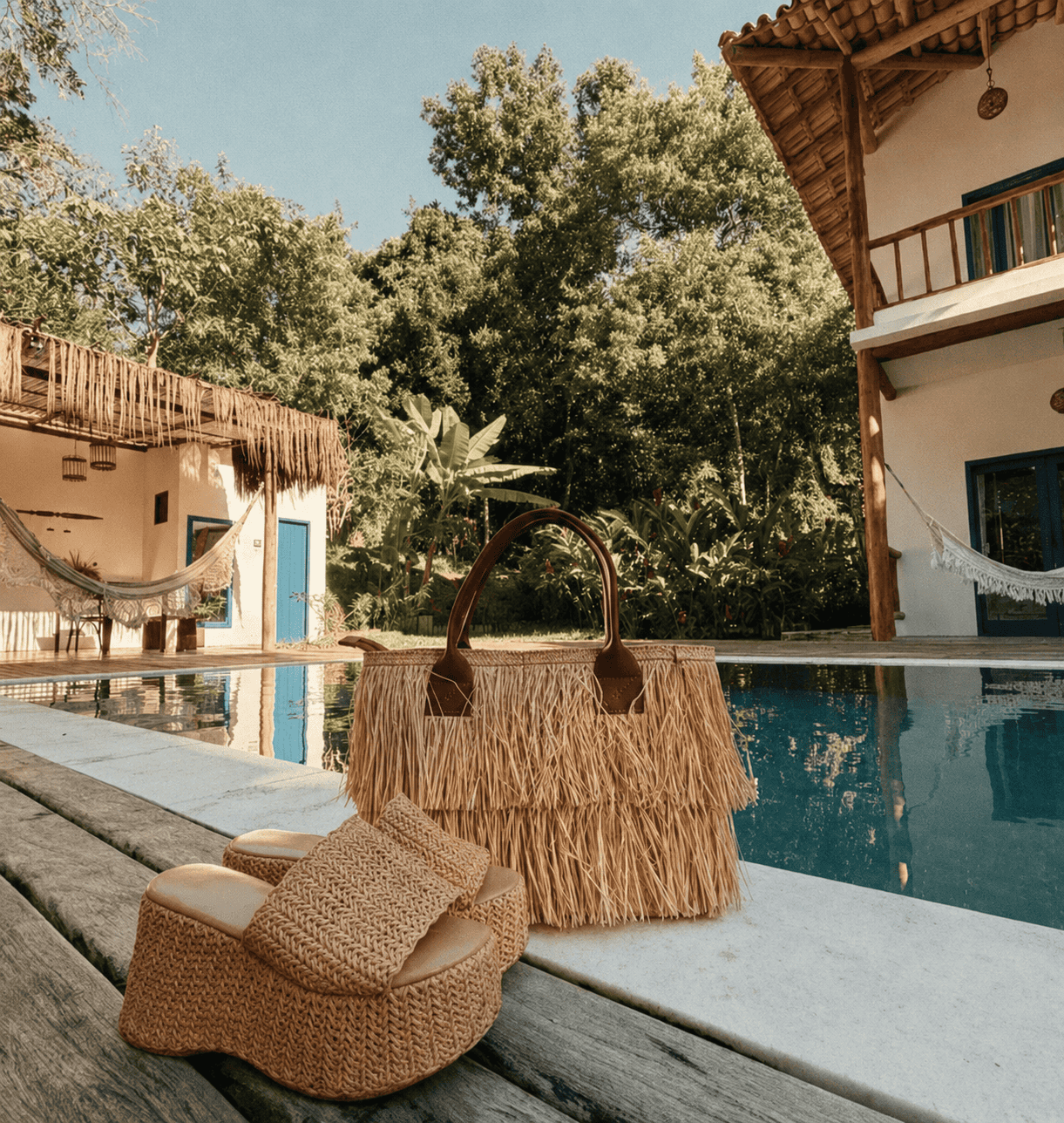 Bolsa de palha e sandálias na borda da piscina