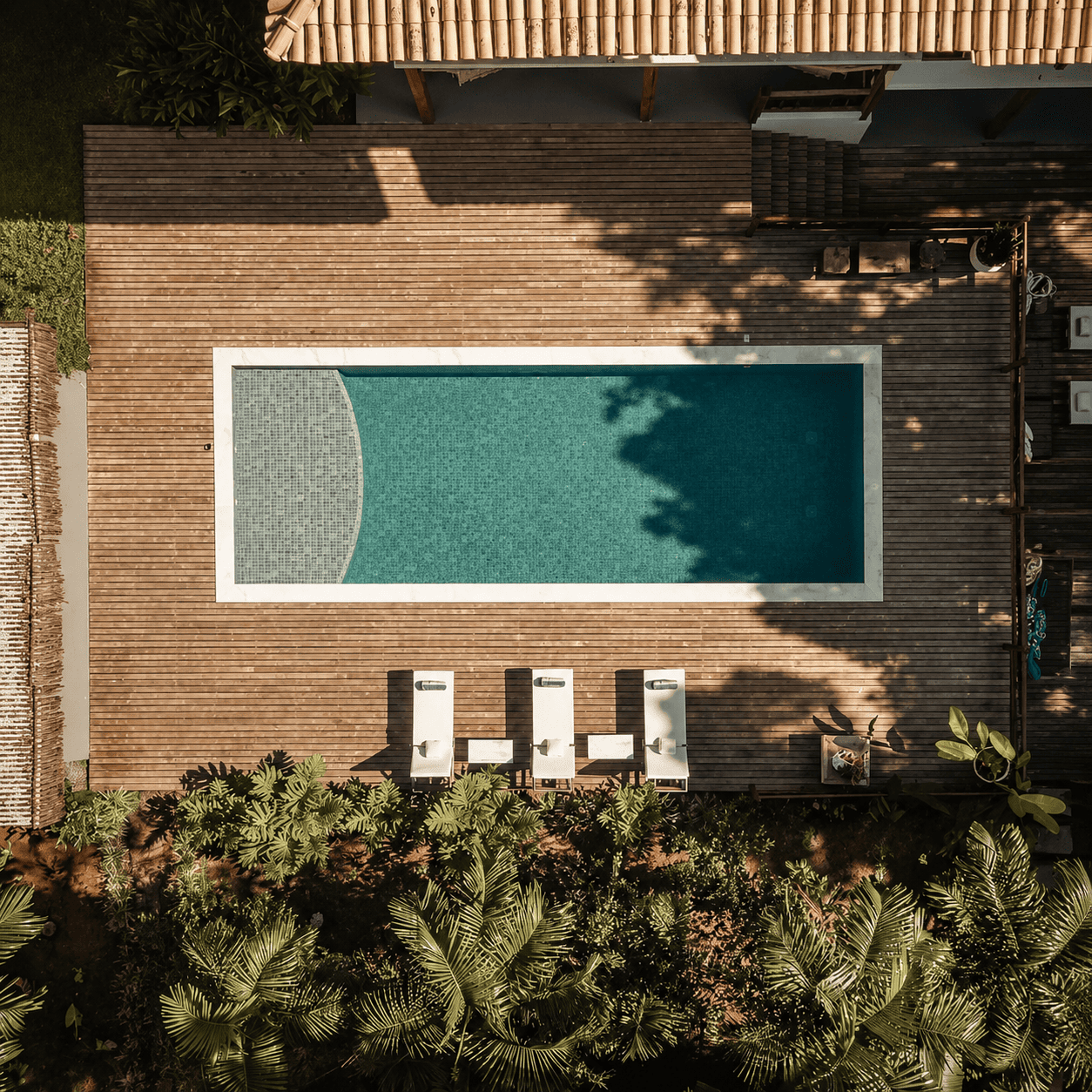 Vista aérea da piscina e do deck de madeira cercados pela mata