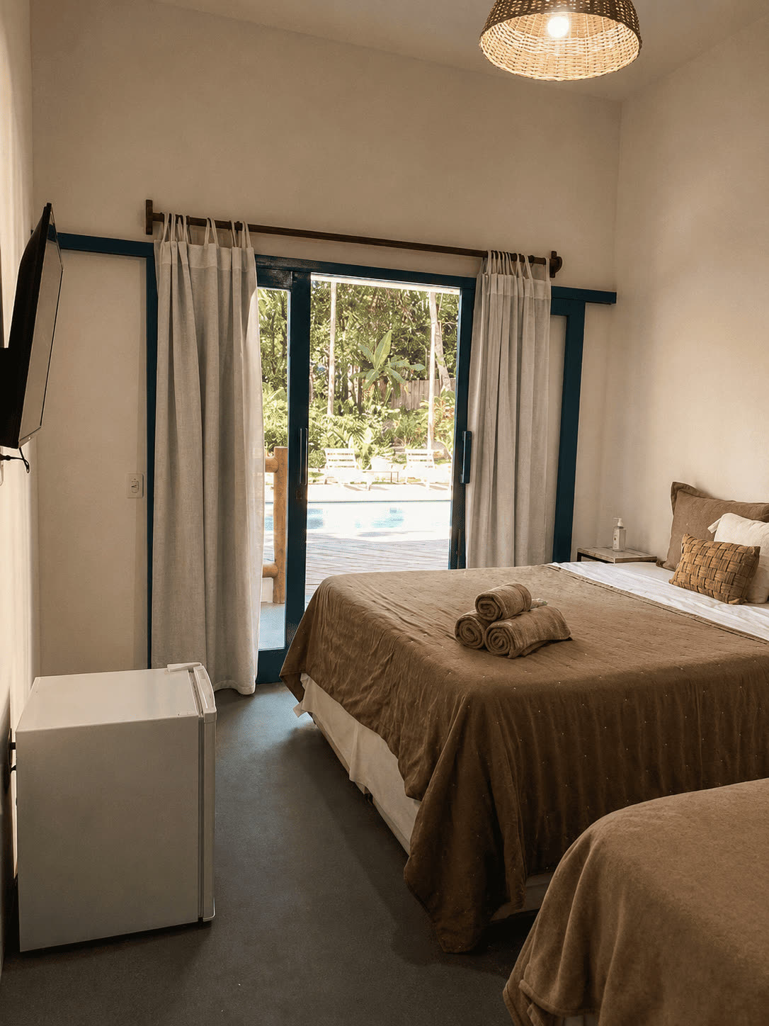 Quarto Triplo com o frigobar, a TV e a piscina vista da varanda.