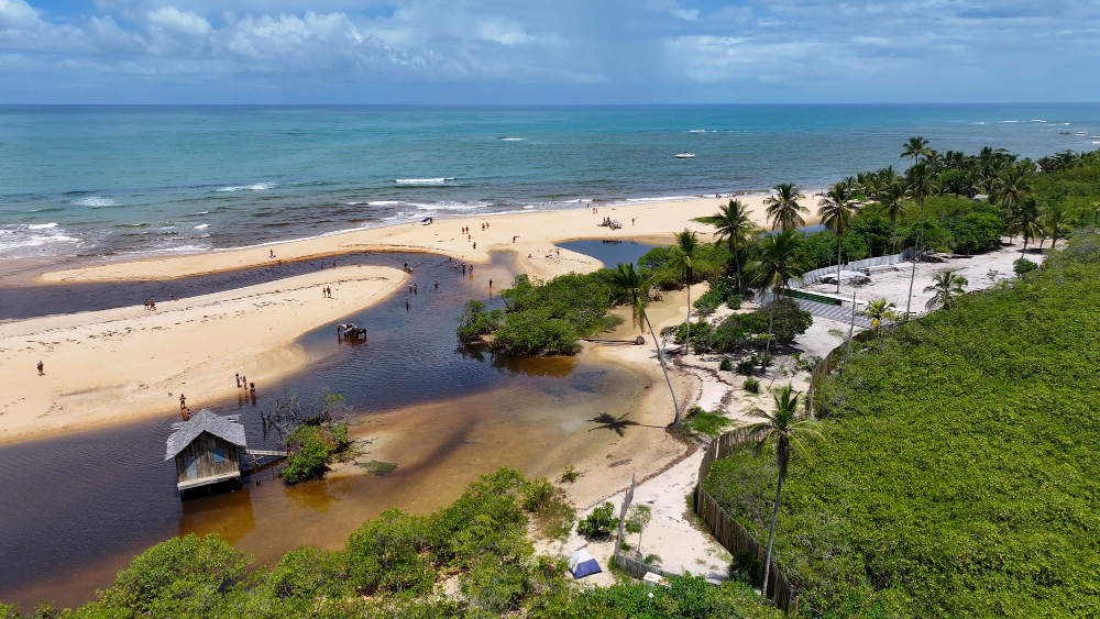 Praia de Trancoso vista do alto da falésia, com o mar calmo e a faixa de areia ao fundo